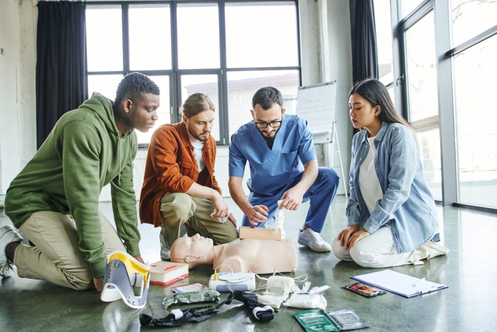 Formateur montrant des gestes de secours à un groupe de participants autour d’un mannequin