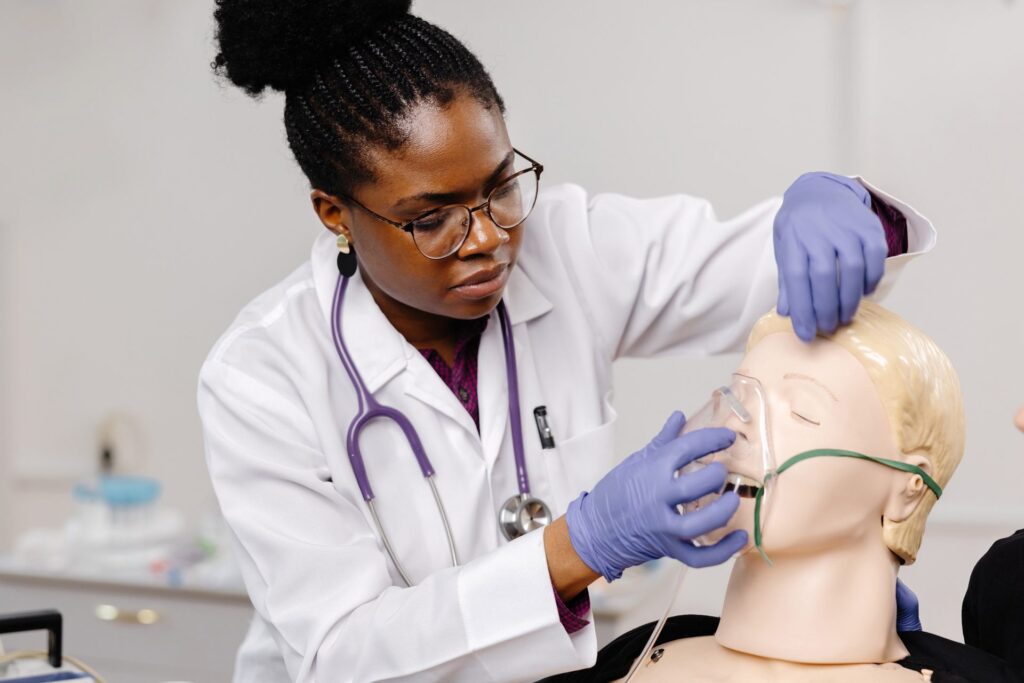 Soignante en blouse qui pose un masque à oxygène sur un mannequin de simulation