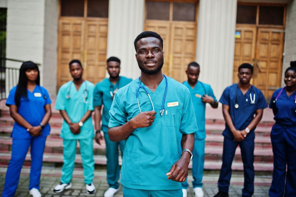 Groupe d’étudiants en santé en tenue médicale, debout devant un bâtiment universitaire